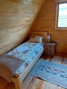 a bed in a wooden cabin with a window at Vule bungalovi in Žabljak