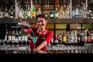 una mujer de pie detrás de una barra con una bebida en Holiday Inn Bangkok Silom, an IHG Hotel, en Bangkok