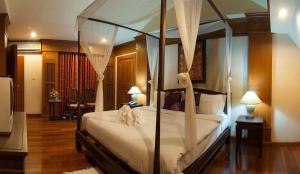 1 dormitorio con cama con dosel y sábanas blancas en Royal Ping Garden and Resort, en Mae Taeng