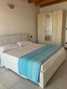 uma cama branca com um cobertor azul em cima em LA CASA DI MARTINA em Castelnuovo del Garda