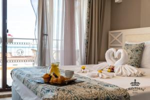 ein Hotelzimmer mit einem Bett mit Schwänen und Essen darauf in der Unterkunft Cristiani Hotel Sozopol in Sozopol