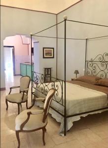 カンピ・サレンティーナにあるCorte san Leonardoのベッドルーム1室(ベッド1台、椅子、ベッドバイザー付)
