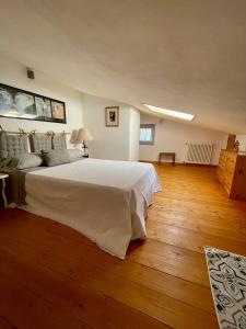 a bedroom with a large white bed and wooden floors at La Casa nel Borgo in Fosdinovo