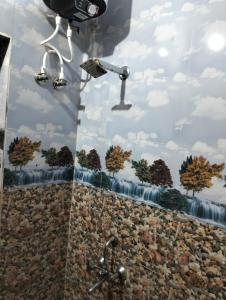 ein Bad mit einer Dusche mit Bäumen an der Wand in der Unterkunft Suresh Guest House & Hotel By WB Inn in Bharatpur