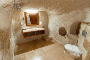 a stone bathroom with a sink and a toilet at Amber Cave Suites in Goreme