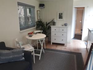 - un salon avec une table blanche et une armoire blanche dans l'établissement Tranquil wood cabin set in a beautiful orchard, à Penzance