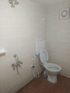 a bathroom with a white toilet and a hose at coorg camping tent stay in Suntikoppa