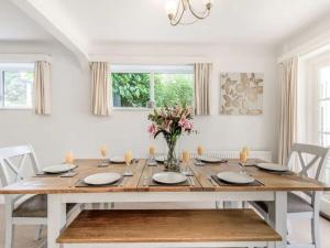 a white dining room with a wooden table and flowers at Lions Lodge: Great location with hot tub in Ringwood