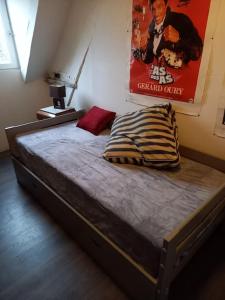 uma cama num quarto com um cartaz na parede em B2 Appartement entier centre ville tout confort em Courtenay