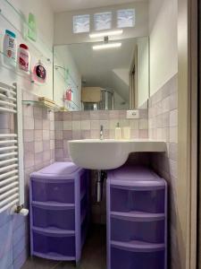 a bathroom with a sink and a mirror and purple stools at La Casa nel Borgo in Fosdinovo