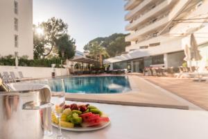 une assiette de fruits sur une table à côté d'une piscine dans l'établissement Hotel Principe Wellness&Spa, à Playa de Palma