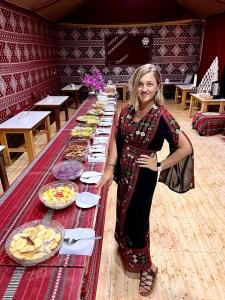 a woman standing in front of a table of food at Bubble RumCamp in Wadi Rum
