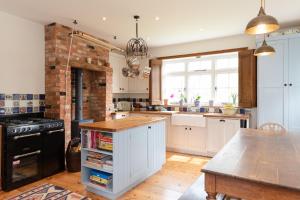a kitchen with white cabinets and a brick wall at Heather Cottage in Brockenhurst