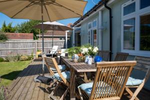 a wooden table and chairs on a deck with an umbrella at Heather Cottage in Brockenhurst