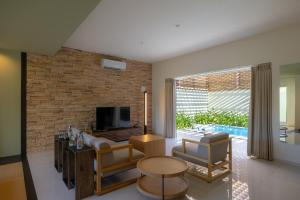 a living room with a tv and a brick wall at Homm Stay Yumiha Okinawa by Banyan Tree Group in Onna