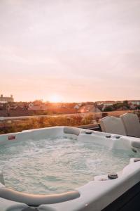 bañera de hidromasaje en un balcón con vistas a la puesta de sol en Hotel Glory en Oradea
