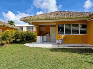 a small yellow house with a chair in the yard at Manbana 333 in Folle Anse