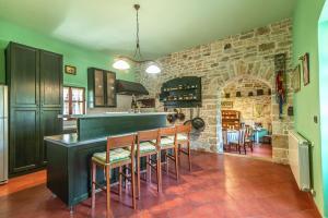 a kitchen with a bar with chairs and a stone wall at Villa Murva in Žminj