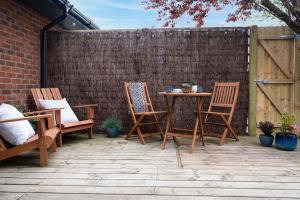 a patio with chairs and a table and a fence at Little Nye in Milford on Sea