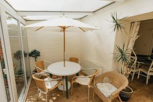 a white table with chairs and an umbrella at FIR TREE COTTAGE - Cosy 3 Bed Cottage in Penrhyn Bay with Beautiful Sea Views and Access to Snowdonia in Llandrillo-yn-Rhôs