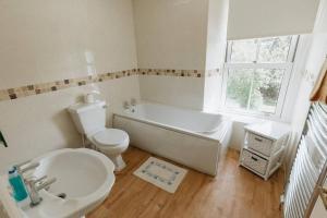 a bathroom with a tub and a toilet and a sink at FIR TREE COTTAGE - Cosy 3 Bed Cottage in Penrhyn Bay with Beautiful Sea Views and Access to Snowdonia in Llandrillo-yn-Rhôs +24 photos