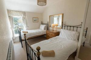 a bedroom with two beds and a mirror at FIR TREE COTTAGE - Cosy 3 Bed Cottage in Penrhyn Bay with Beautiful Sea Views and Access to Snowdonia in Llandrillo-yn-Rhôs