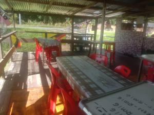 stół z czerwonymi krzesłami oraz stół ze stołem sidx sidx w obiekcie Mulu Homestay w mieście Mulu