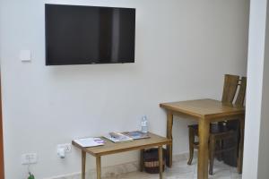uma sala com duas mesas e uma televisão na parede em Tenda Suites and Restaurant em Entebbe