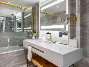 a bathroom with a white sink and a shower at Sofitel Warsaw Victoria in Warsaw
