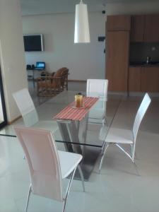 a glass table with white chairs and a coffee cup on it at Apartamentos Santiago - Maio in Vila do Porto