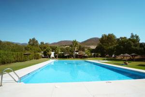 una piscina en un complejo con montañas en el fondo en Kampaoh Valdevaqueros, en Tarifa