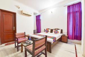 FabHotel Gitanjali في جايبور: غرفة نوم مع سرير مع ستائر أرجوانية وطاولة