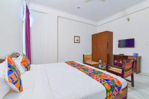 FabHotel Gitanjali في جايبور: غرفة نوم بسرير وطاولة وكرسي