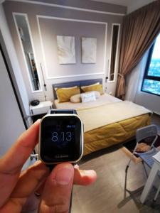 a person holding a watch in front of a bedroom at FREE NETFLIX! ZAs Suite at Troika Residence, KB in Kota Bharu