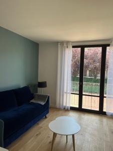 ein Wohnzimmer mit einem blauen Sofa und einem Tisch in der Unterkunft STUDIO PROCHE PARIS VERSAILLES in Villennes-sur-Seine