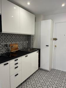 eine Küche mit weißen Schränken und einer schwarzen Arbeitsplatte in der Unterkunft STUDIO PROCHE PARIS VERSAILLES in Villennes-sur-Seine