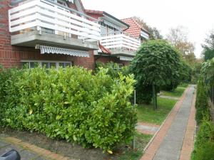a building with a balcony and some bushes at Ferienwohnung 1066 App 3 in Tossens in Butjadingen OT Tossens