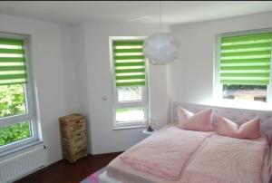 a bedroom with a bed with pink pillows and windows at Top Apartment in Langenhagen in Hannover