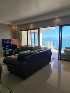 a living room with a couch and a television in a house at Bikini Beach Manor in Gordonʼs Bay