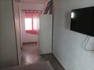 Habitación pequeña con nevera blanca y TV. en Spirit of Costa Calma en Costa Calma