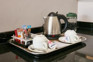 a tray with a tea pot and cups on a counter at Regent Select Hotel in Gaborone