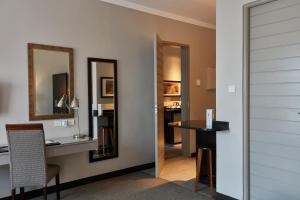 una camera con scrivania, tavolo e specchio di Regent Select Hotel a Gaborone
