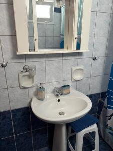La salle de bains est pourvue d'un lavabo blanc et d'un miroir. dans l'établissement Villa Magda., à Agios Georgios Pagon