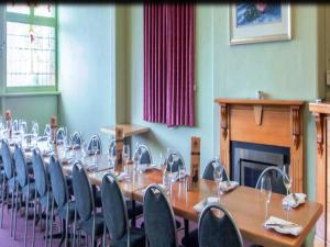 a room with a long table and chairs and a fireplace at Holgate Brewhouse in Woodend