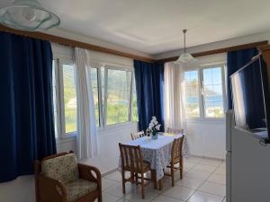 - une salle à manger avec une table, des chaises et des fenêtres dans l'établissement Villa Magda., à Agios Georgios Pagon
