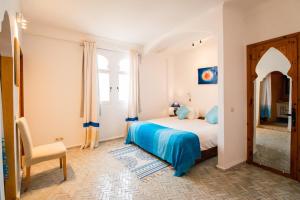 a bedroom with a bed and a chair and a window at Dar Liouba Hotel in Essaouira
