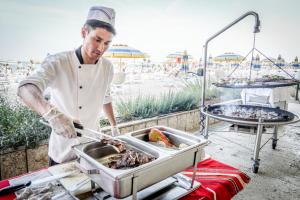 a chef preparing food in a pan on a grill at Hotel Gergana - Ultra All Inclusive in Albena