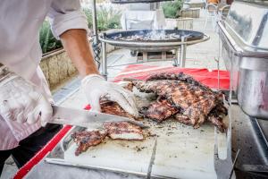 a man is preparing meat on a grill with a knife at Hotel Gergana - Ultra All Inclusive in Albena