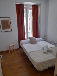 1 dormitorio con 1 cama y una ventana con cortinas rojas en Espoz habitaciones, en Madrid