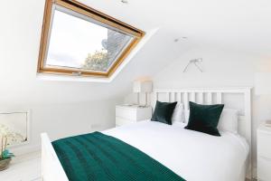 a bedroom with a white bed with green sheets and a window at PenthouseStays Notting Hill - Chic 2 Bedroom Apartment w/ King Beds - near Portobello Road & Kensington High Street in London